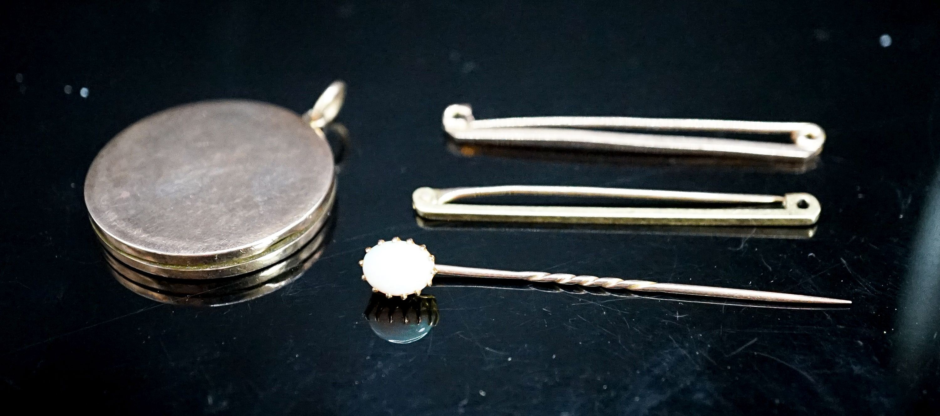 An 18ct bar brooch, 50mm, 2 grams, a 9ct bar brooch, 1.8 grams, a white opal set stick pin and a yellow metal locket.